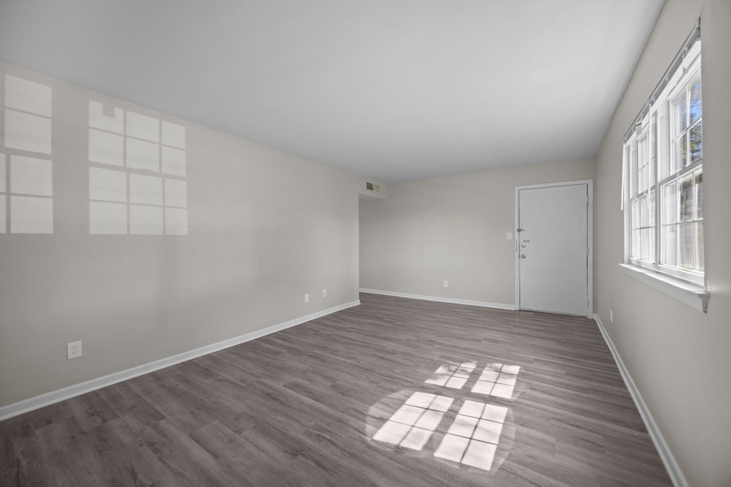 A room with a wooden floor and a window letting in sunlight.