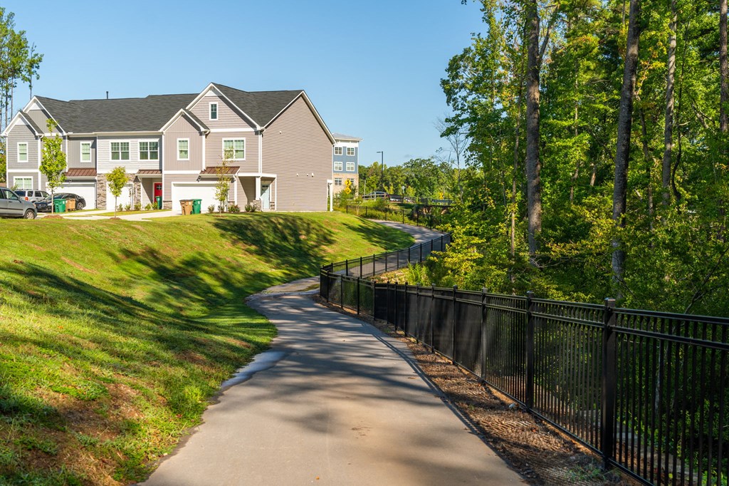a sidewalk leading to a house on a hill with trees