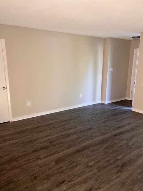 an empty living room with wood floors and white walls