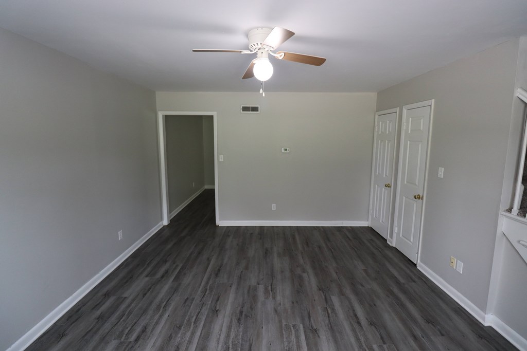 A room with a ceiling fan and wooden flooring.