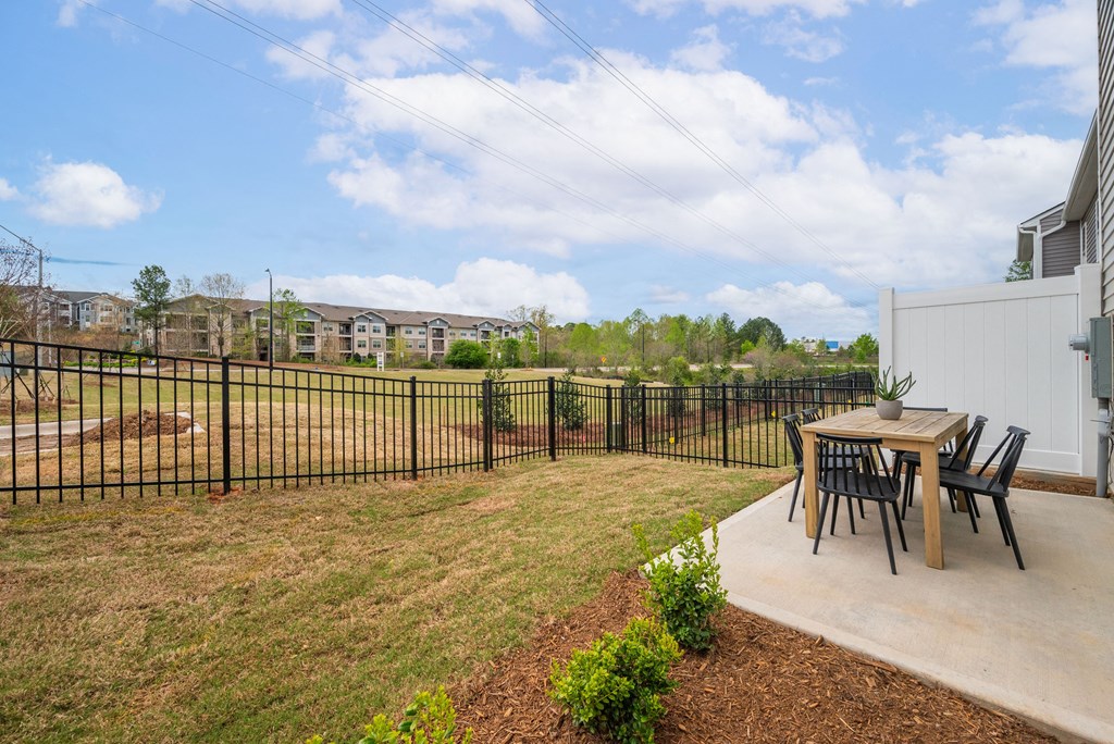 a patio with a table and chairs in front of a fence