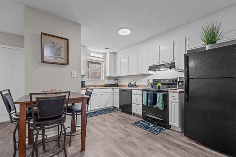 A kitchen with a black refrigerator and wooden dining table.