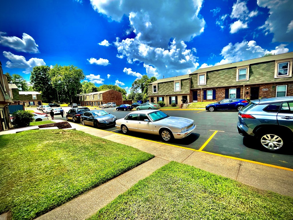 a parking lot with cars parked in front of apartment buildings