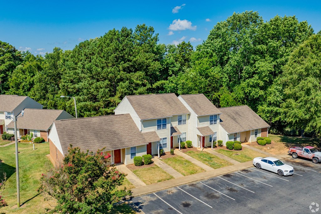A white car is parked in a parking lot in front of a building.