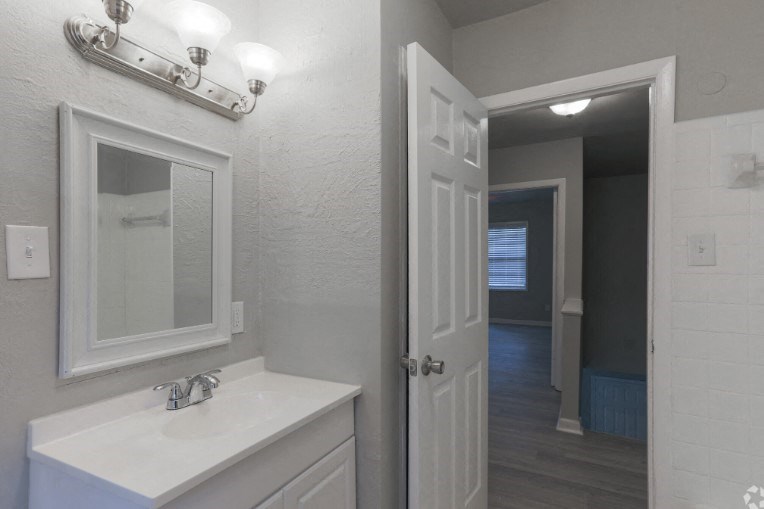 a bathroom with a sink and a mirror and a hallway