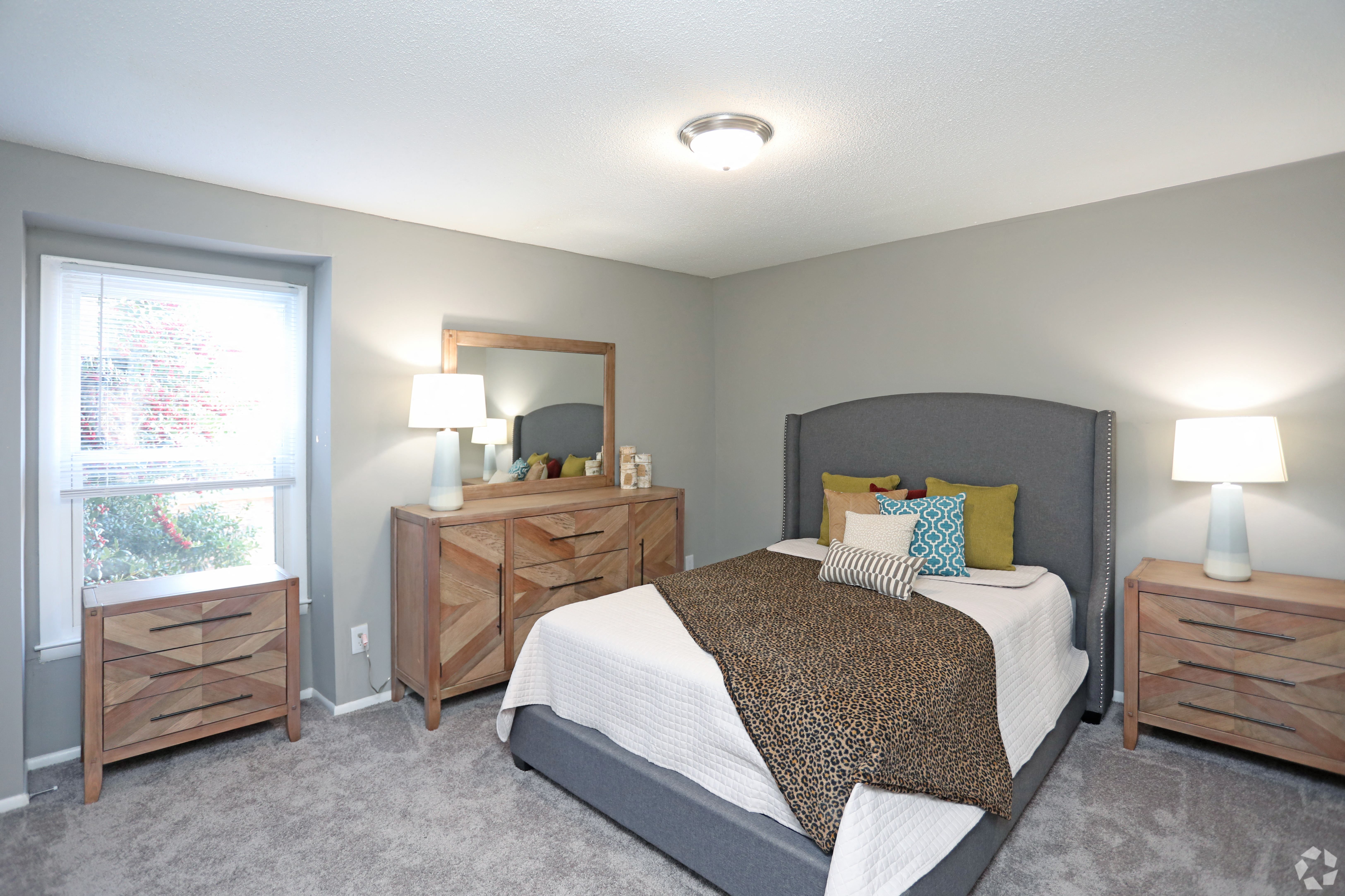 a bedroom with a bed and dressers and a window