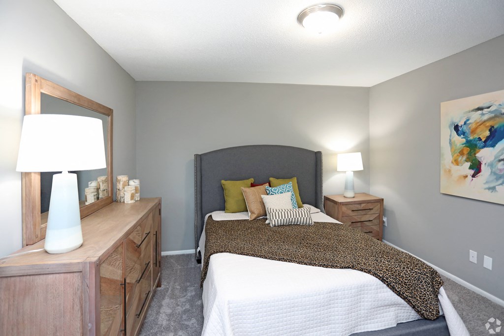 a bedroom with a bed and a dresser and a mirror