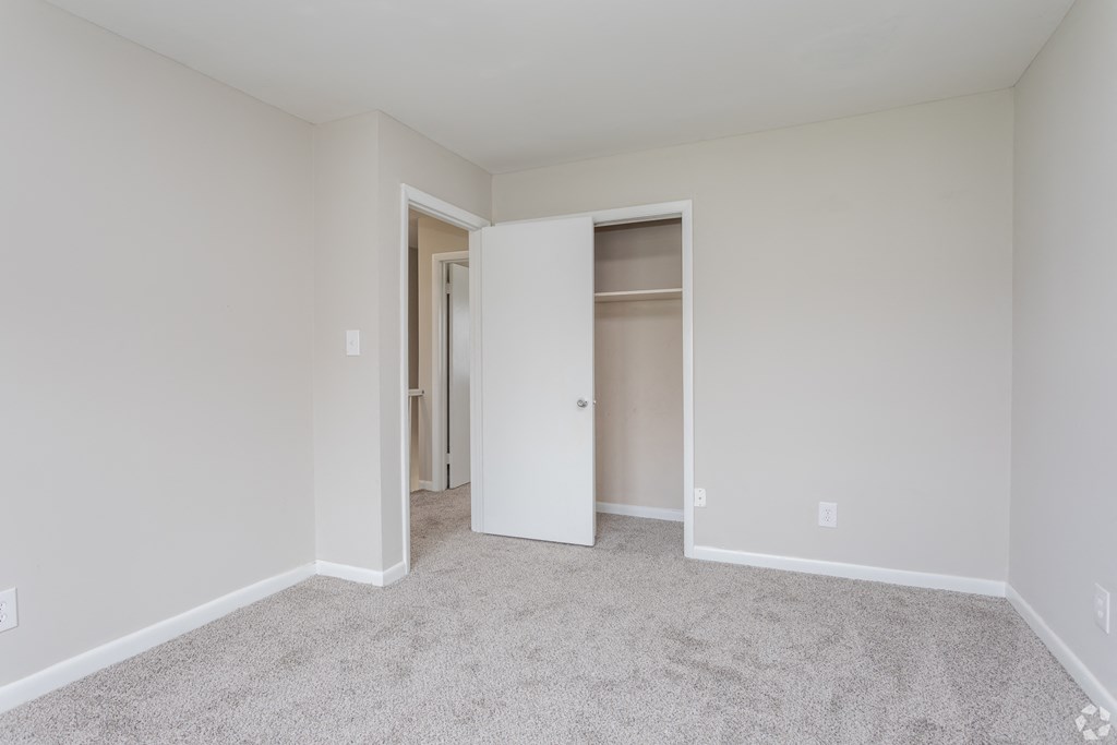 A white room with a carpeted floor and a doorway leading to another room.