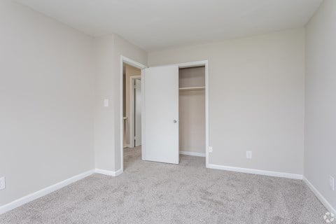 A white room with a carpeted floor and a doorway leading to another room.