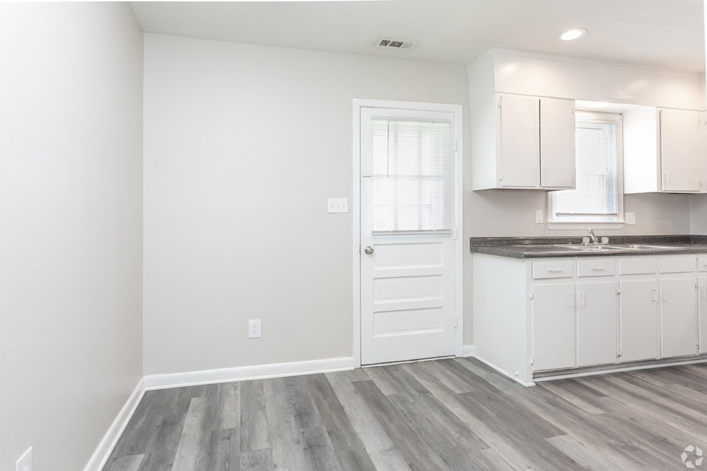 an empty kitchen with white cabinets and a white door