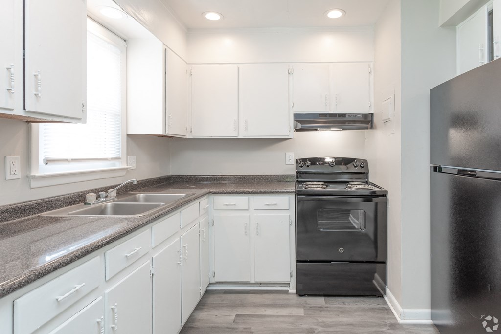 A kitchen with white cabinets and a black refrigerator.