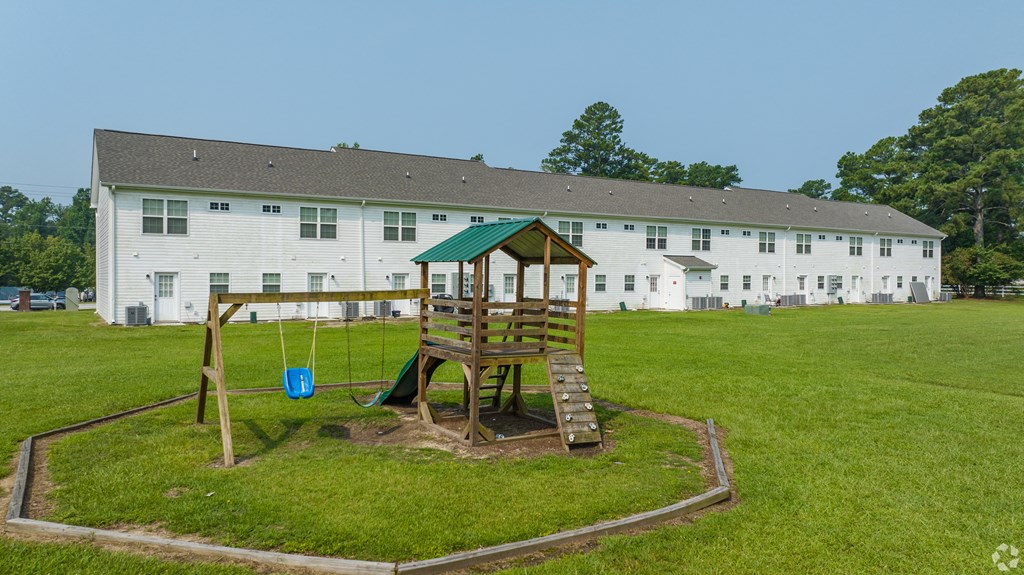 a playground with a swing set in front of a white building