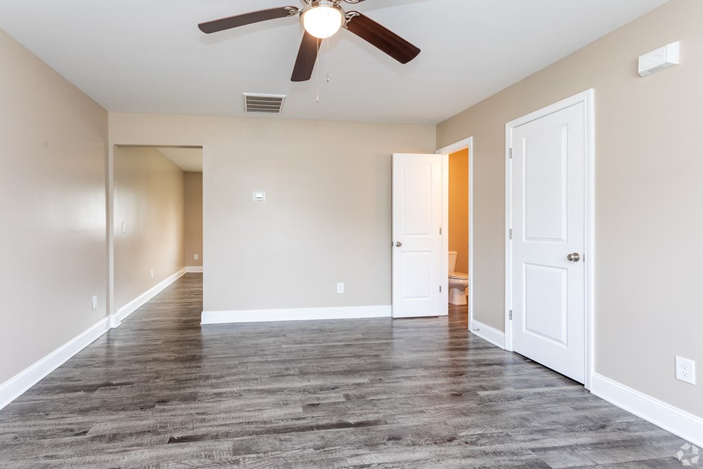 A room with a ceiling fan and wooden flooring.