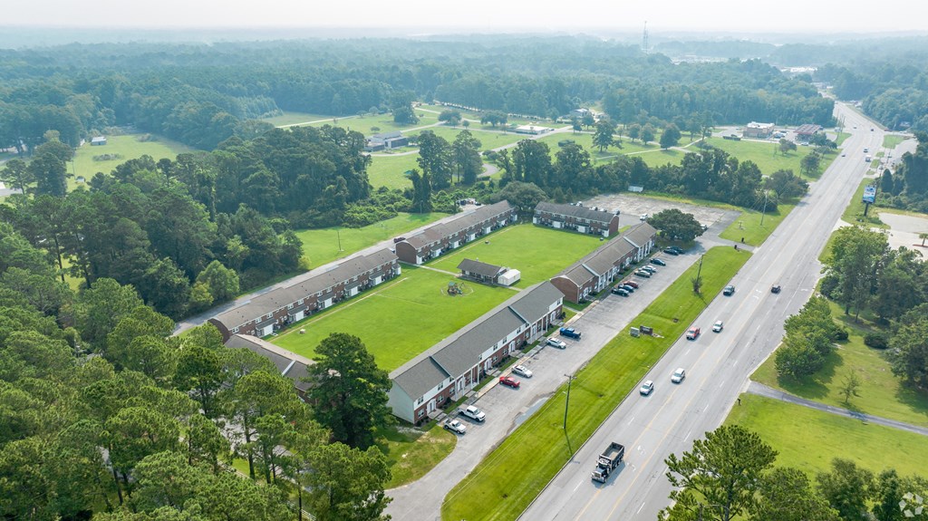 an aerial view of a building next to a field and a highway