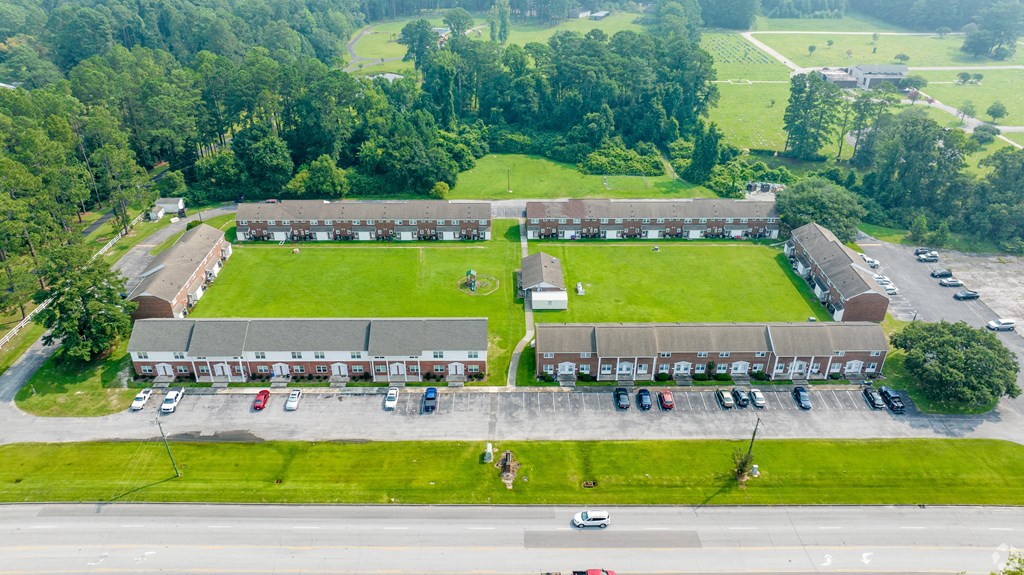 an aerial view of a building with a field and a parking lot