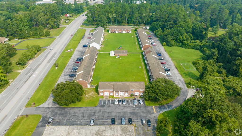 an aerial view of a school with a grassy field and a highway with cars
