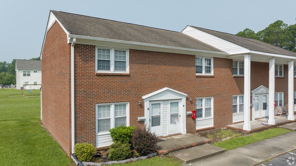 a red brick house with white columns and a red mailbox
