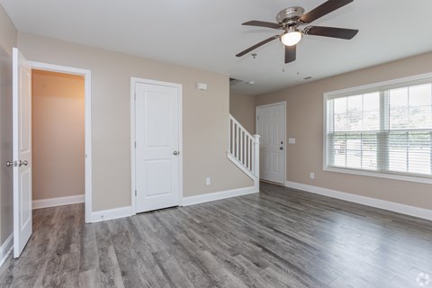 an empty living room with a ceiling fan and a window