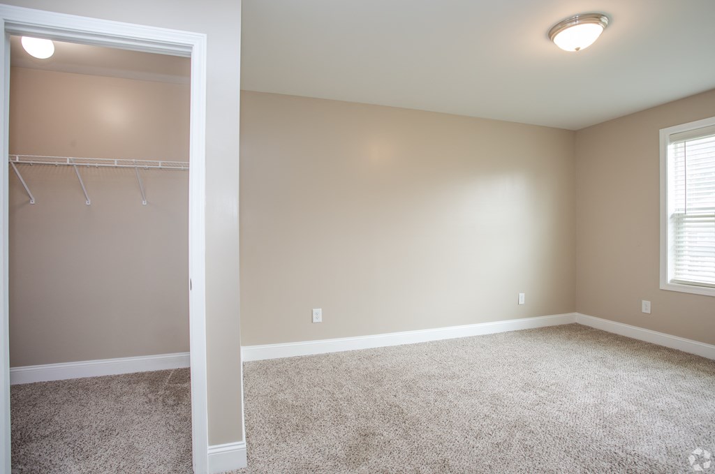 an empty living room with carpet and a closet