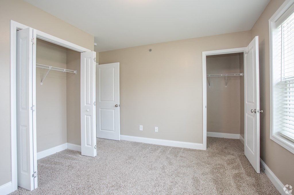 A room with a carpeted floor and two open doors.