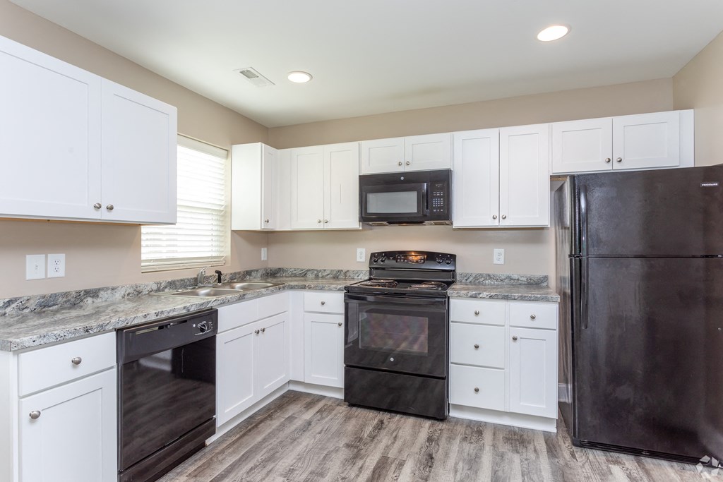 a kitchen with white cabinets and black appliances