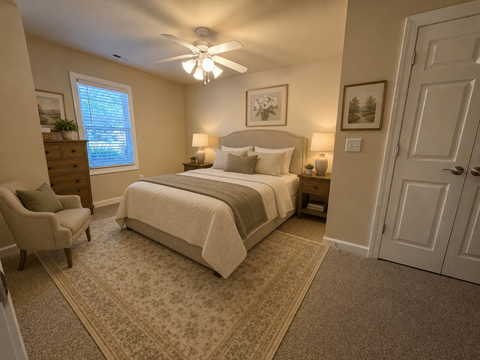 A bedroom with a bed, chair, and ceiling fan.