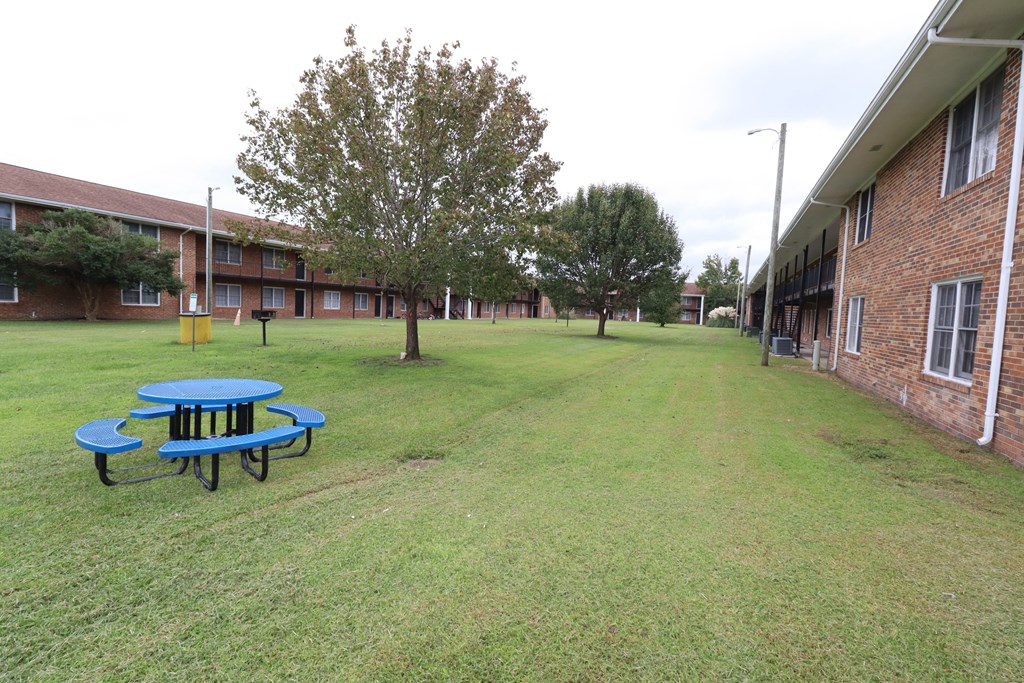 a large yard in front of a building with a blue picnic table