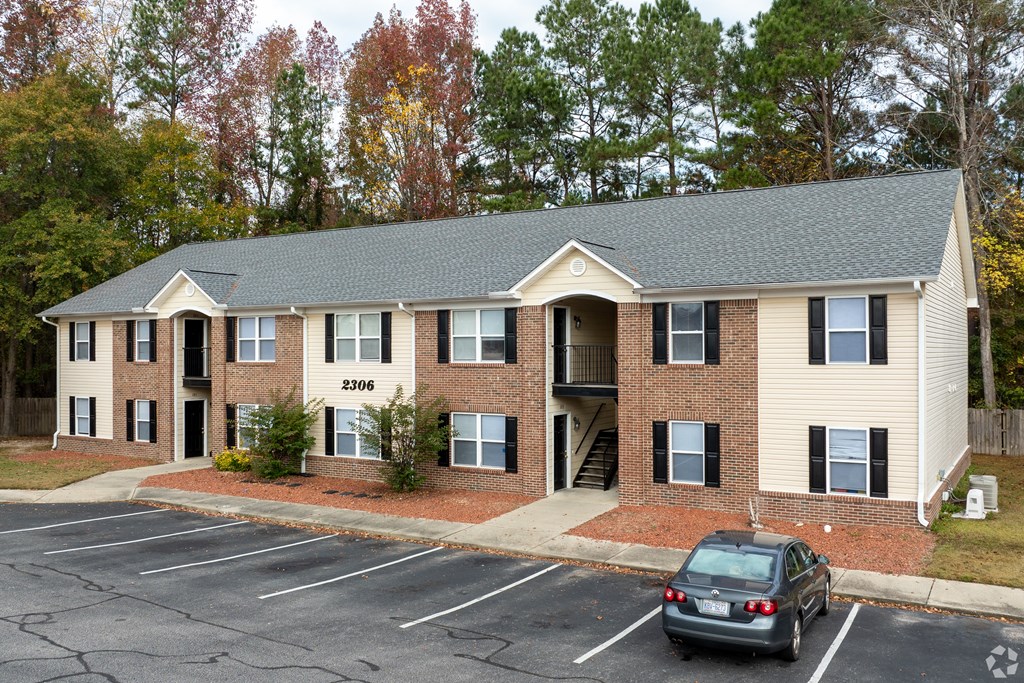 A car is parked in a parking lot in front of a building with the number 2306 on it.