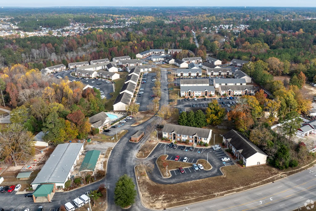 An aerial view of a parking lot and buildings with trees in the background.