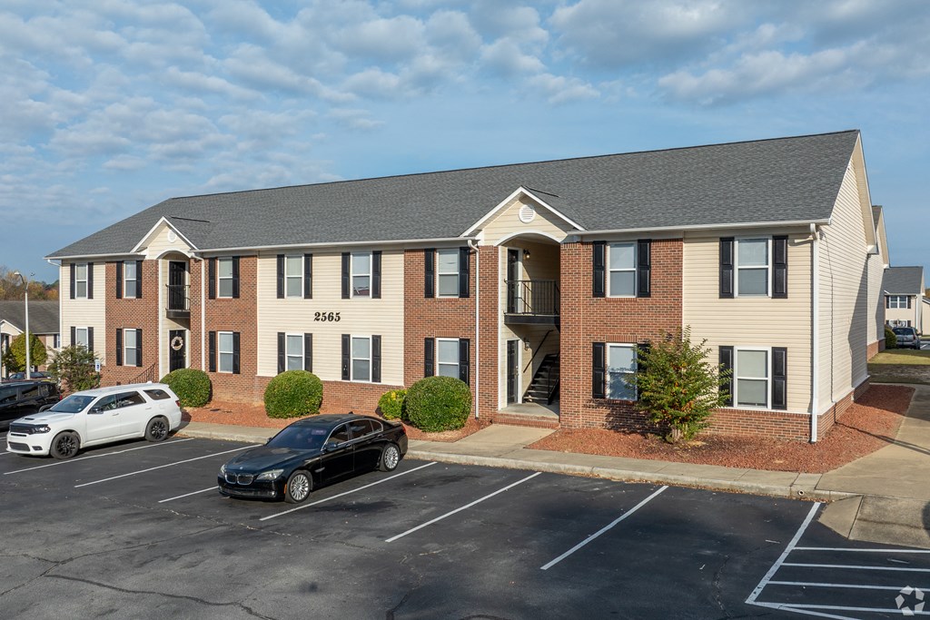 A black car is parked in front of a building with the number 2565 on it.