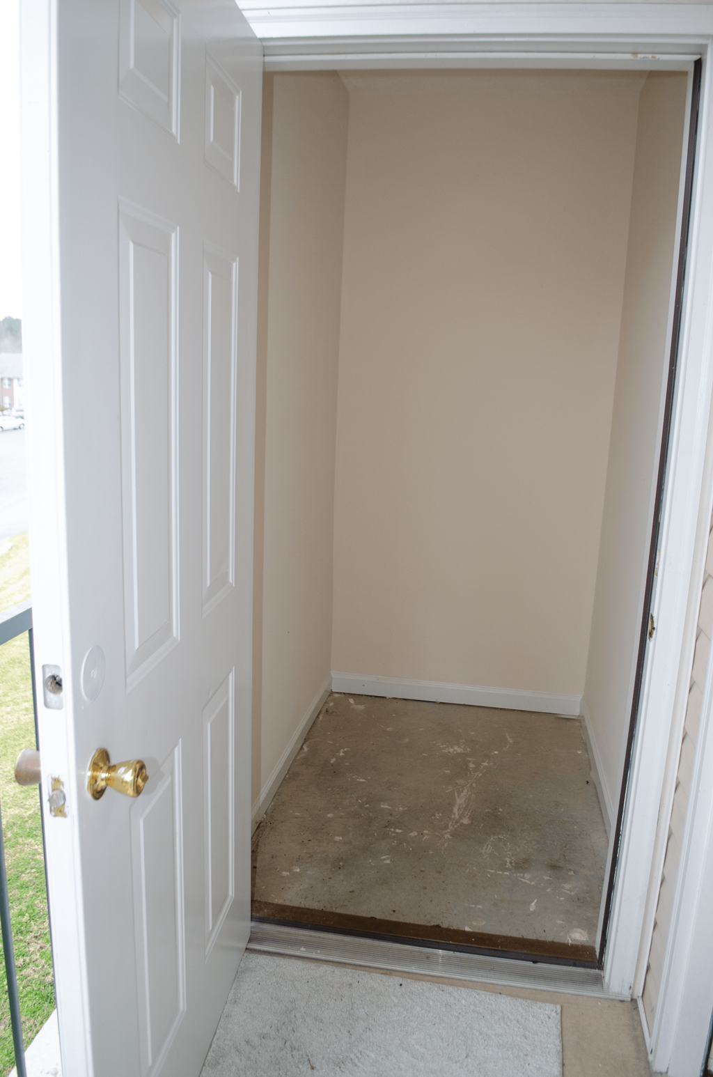 a small room with a white door and a carpeted floor