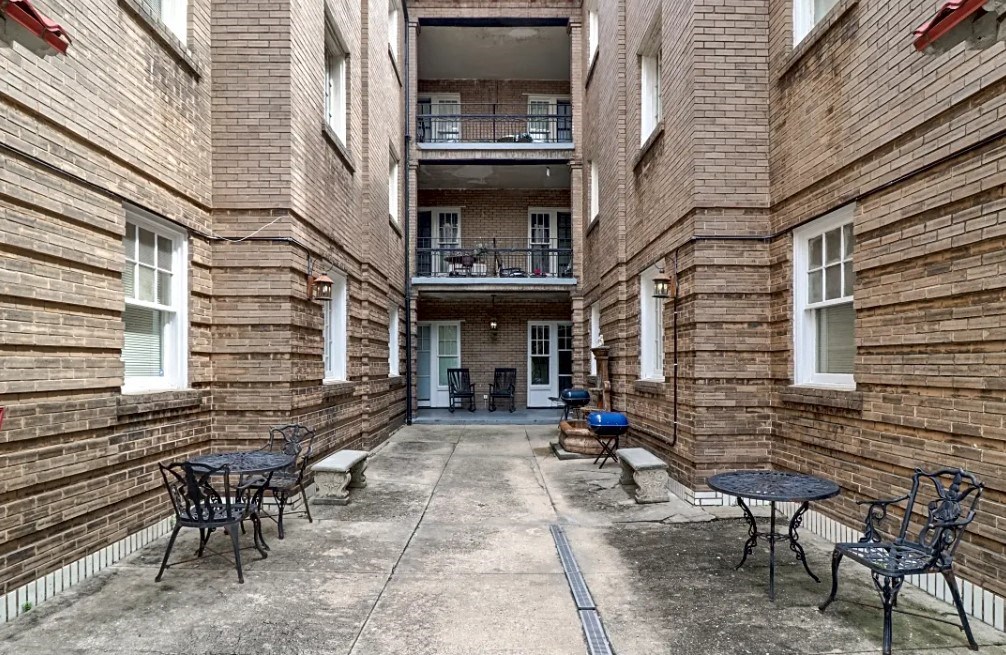the courtyard of an apartment building with tables and chairs