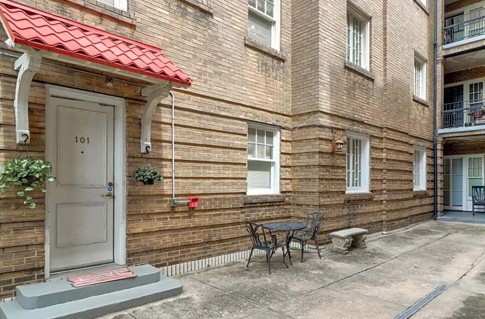 the front door of a brick apartment building with a table and chairs