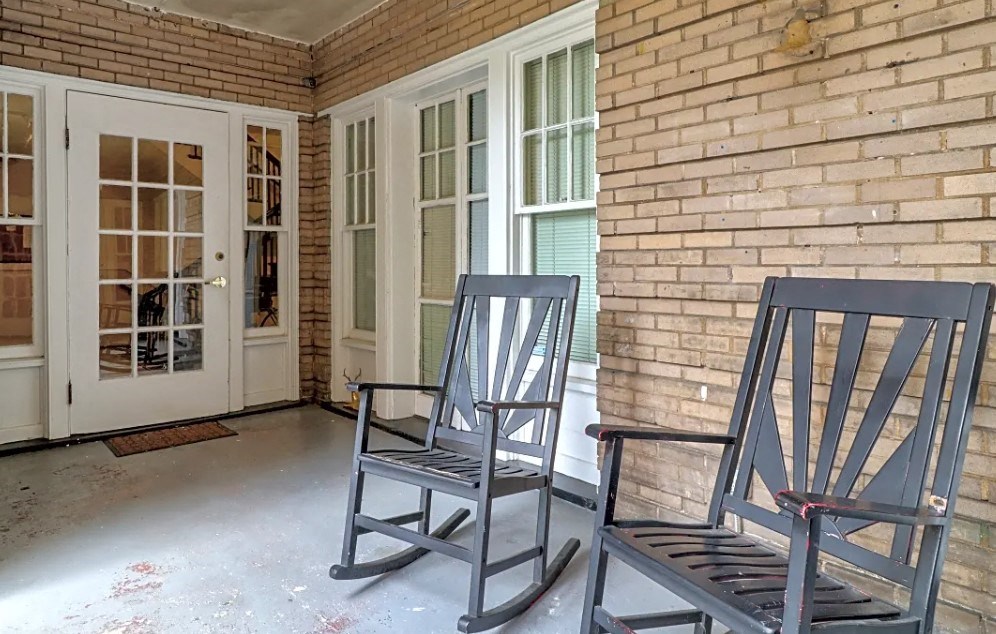 two rocking chairs on the front porch of a brick house