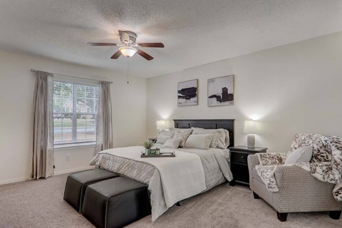 A bedroom with a large bed and a chair.