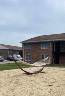 a hammock in the sand in front of a house