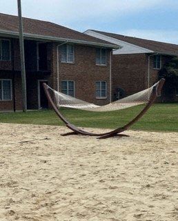 a large hammock in the sand in front of a building