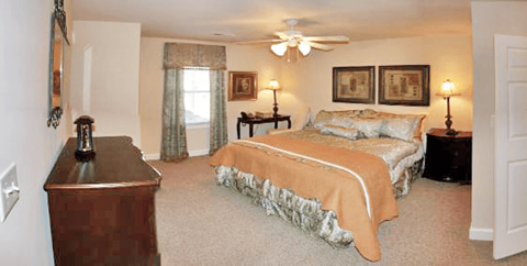 A bedroom with a bed, dresser, and ceiling fan.