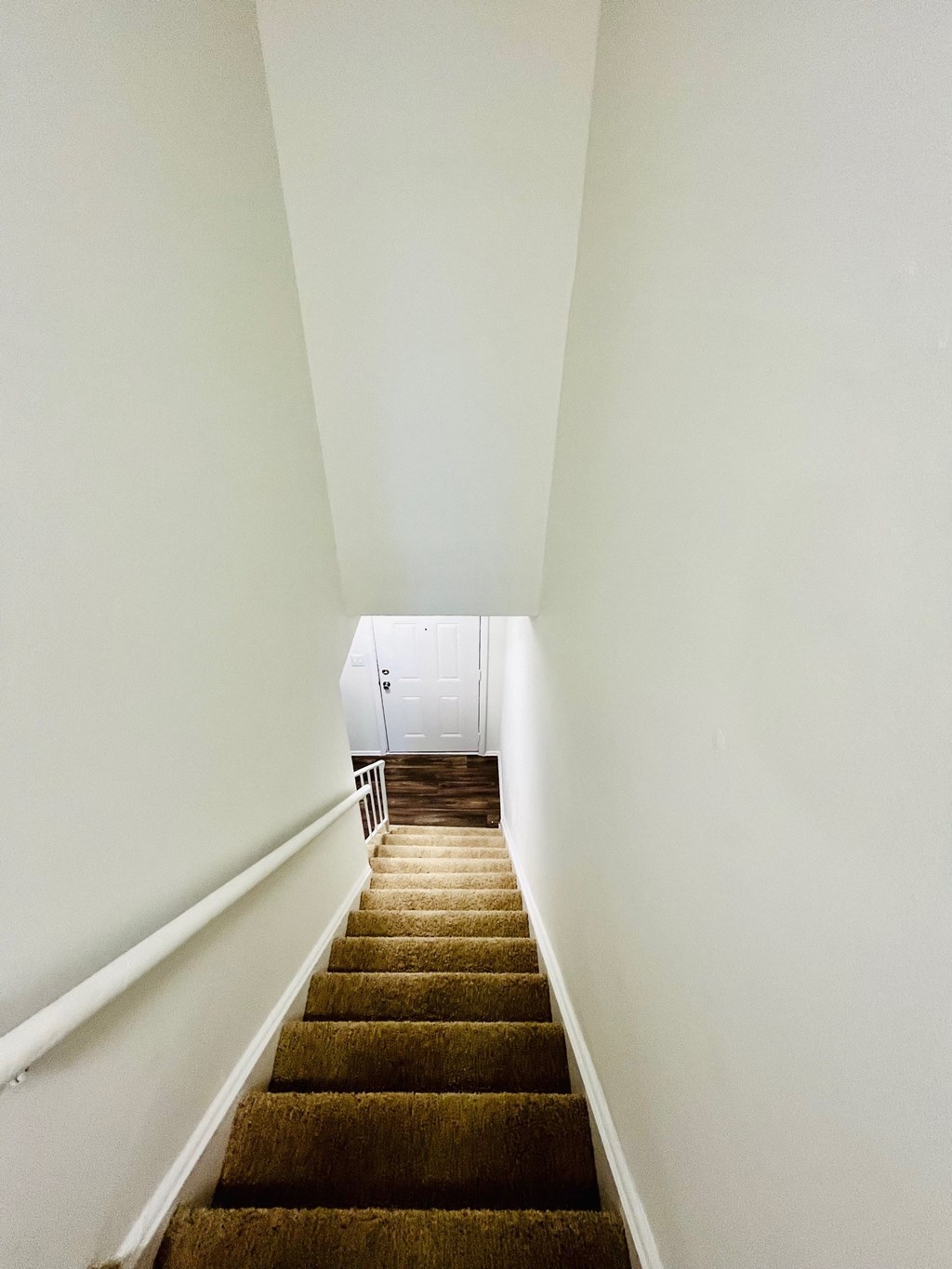 a flight of stairs with brown carpet and white walls