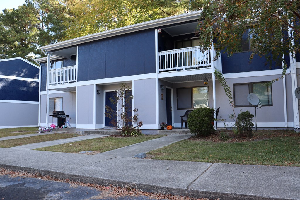 a blue and white house with a yard and a sidewalk
