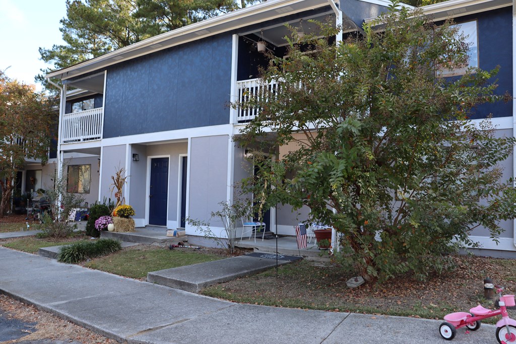 a blue house with a childs pink scooter in front of it
