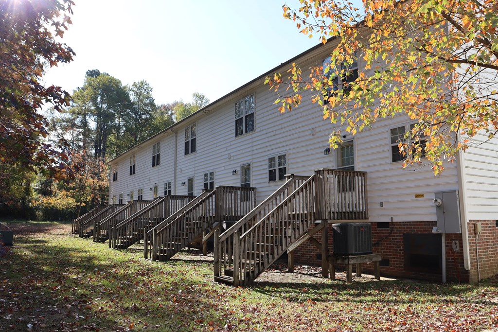 the outside of a white building with two sets of wooden stairs