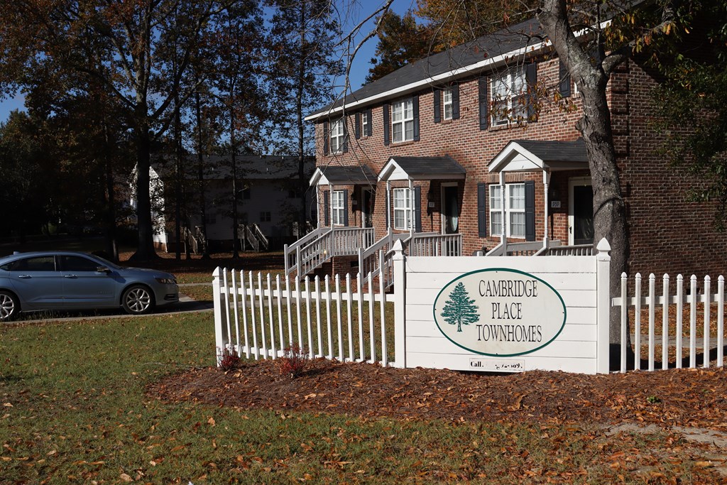 a sign in front of a house with a white fence