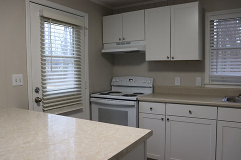 a kitchen with white cabinets and a stove and a window