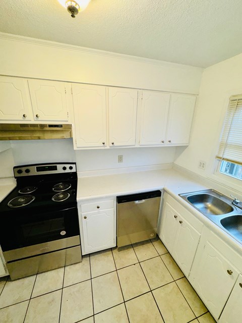 A kitchen with white cabinets and a black stove top oven.