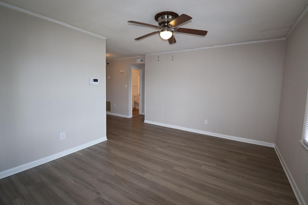 an empty living room with wood floors and a ceiling fan