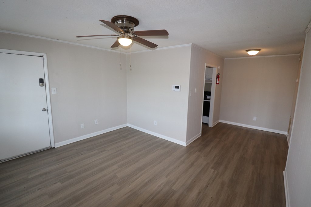 an empty living room with wooden floors and a ceiling fan