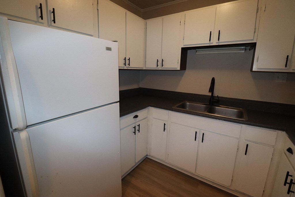 an empty kitchen with white cabinets and a refrigerator