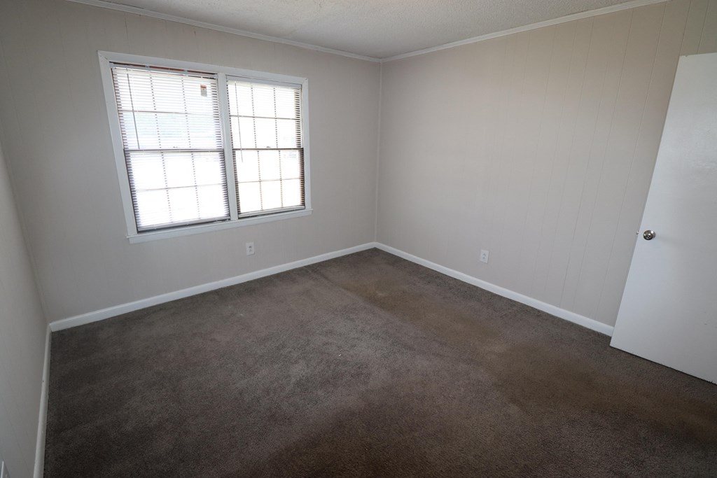 a carpeted room with a window and a door
