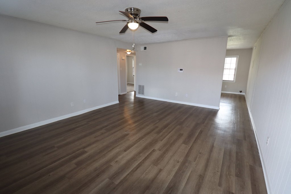 an empty living room with wooden floors and a ceiling fan